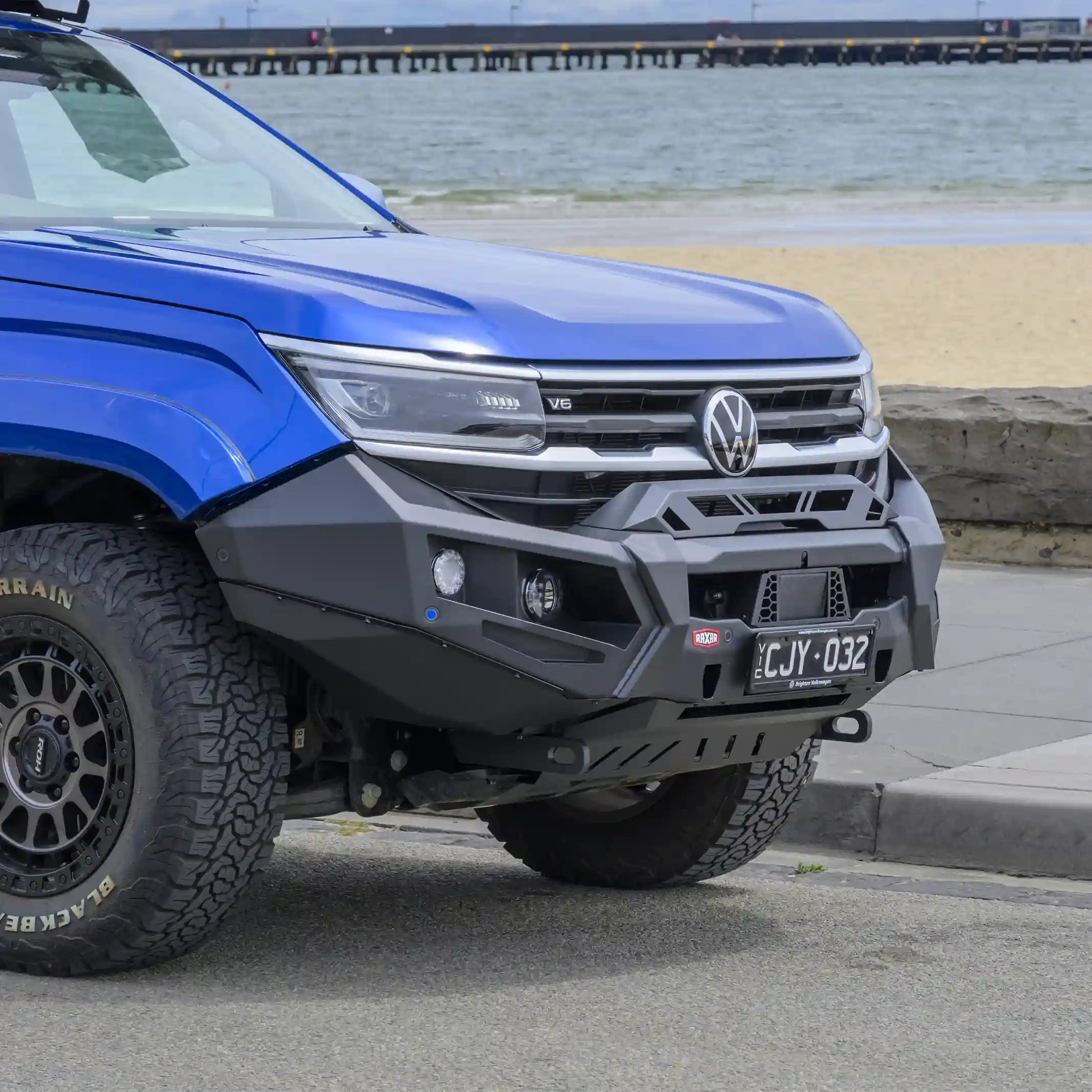 Shown from the left side, the VW Amarok installed no loop bull bar from Elevated 4x4 demonstrates durable RAXAR construction with underbody bash plates, split-pan design, and factory sensor compatibility. Designed for tough Australian terrain, it combines strength, style, and everyday 4WD practicality.