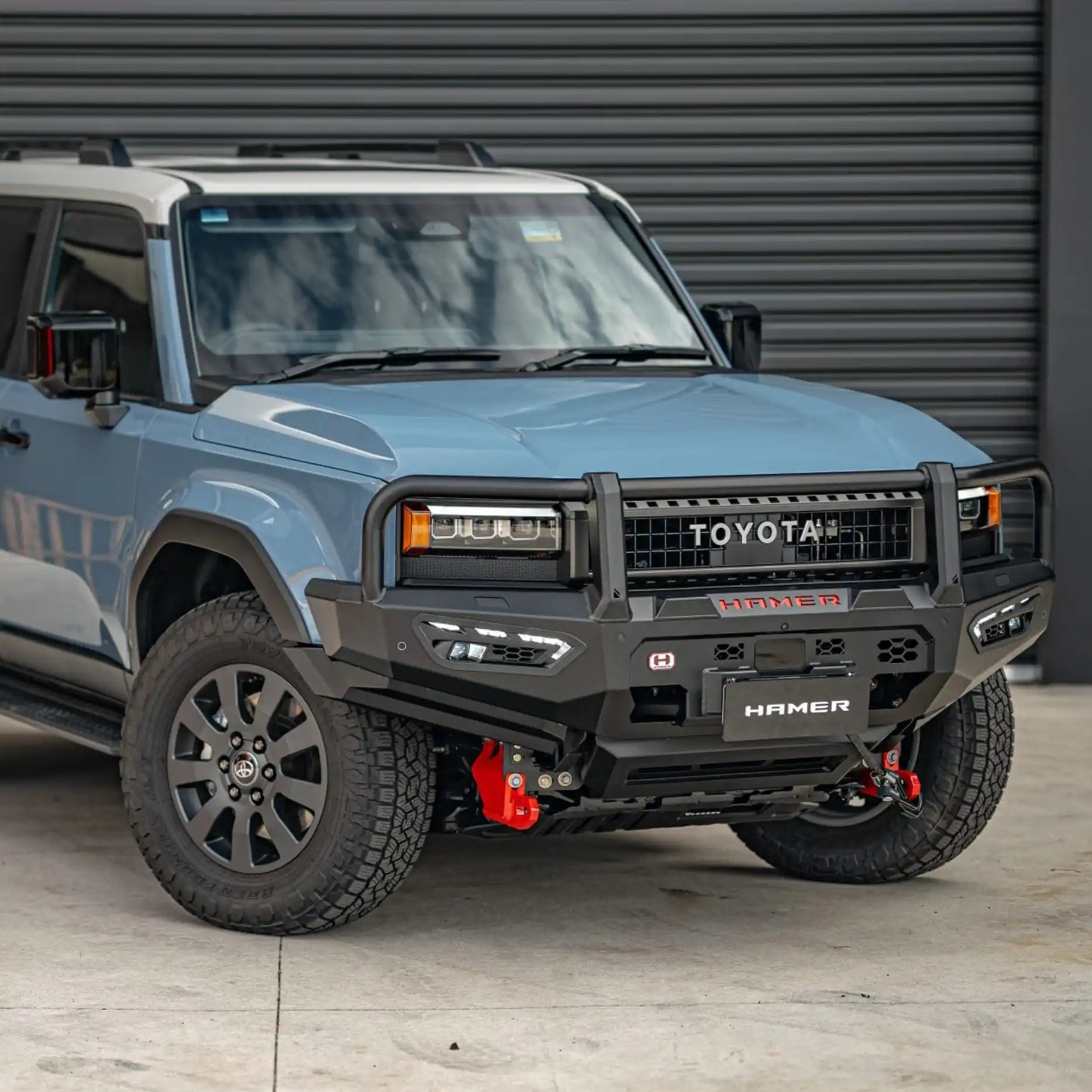 Left side angle of Hamer Atlas Plus Series Bull Bar on Toyota Prado 250 Series 2024 – Present, highlighting matte black powder-coated finish, parking sensor compatibility, and rugged 3mm steel construction.