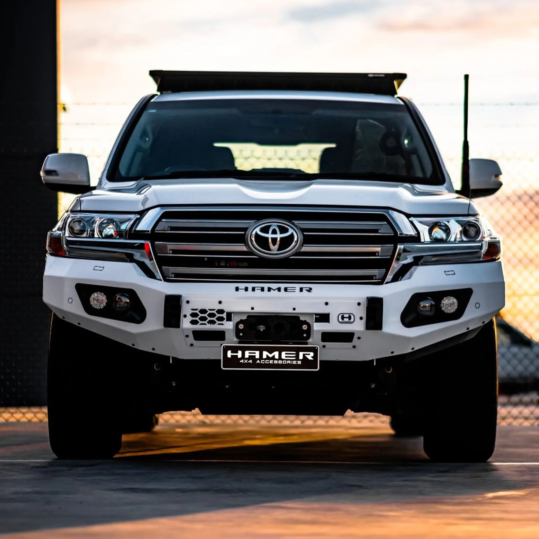 Front view of Landcruiser 200 Series with Hamer King Series Bull Bar, matte black bumper replacement with LED lights, winch access and ADR safety.